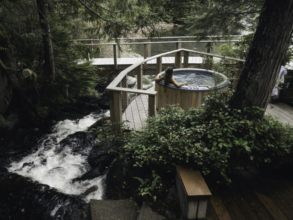Hot tub on a forest deck beside a rushing creek